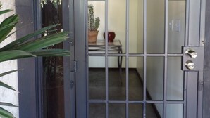 Een metalen poort met een sleutelgat en een kleine tafel met een bloempot erin.