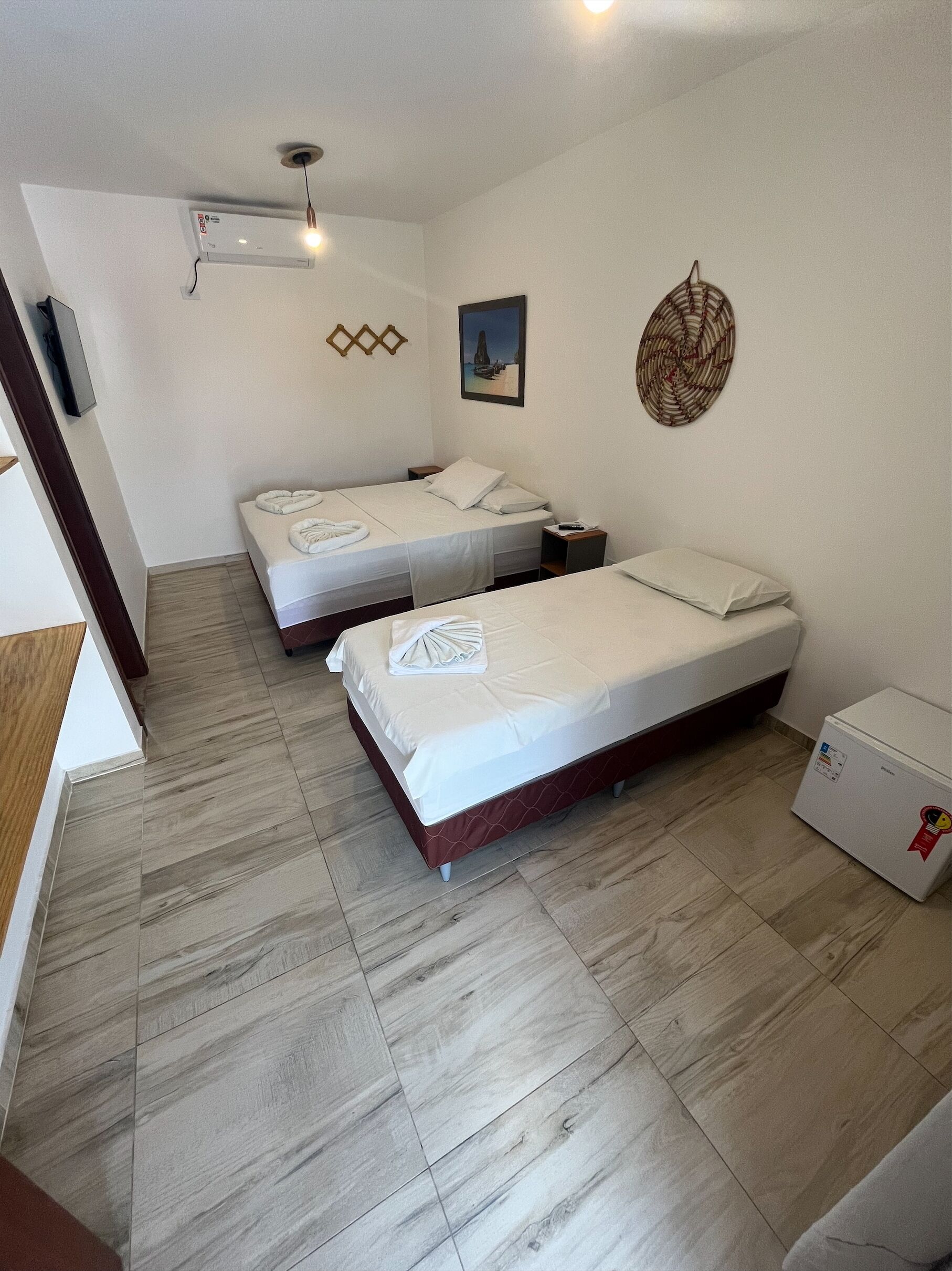 A hotel room with two beds, a small refrigerator, and a ceiling fan.