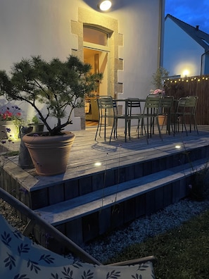 A wooden deck with outdoor furniture, a potted plant, and a stone wall.