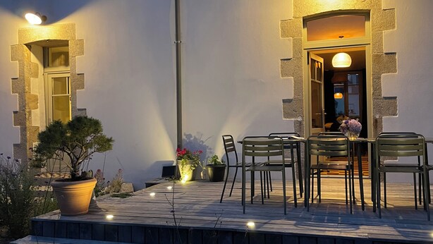 An outdoor seating area with a table and chairs, potted plants, and a staircase leading to an entrance. - Retro style seaside house, La Torche surf spots, Pors Carn, pets allowed (Penmarc'h)