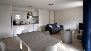 Ein moderner, kompakter Wohnraum mit Küche, Essbereich und Sitzgelegenheit.