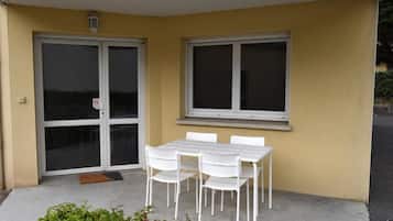 A covered patio with a table and chairs, a sliding glass door, and a window.
