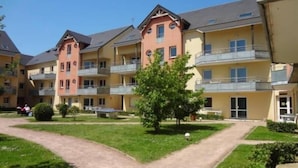 Ein Innenhof mit einem zentralen Weg, umgeben von mehrstöckigen Gebäuden mit Balkonen und einem kleinen Baum.