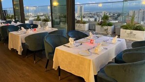 A rooftop restaurant with tables set for dining, overlooking a cityscape. - Hotel Atlantis Alger (Algiers)