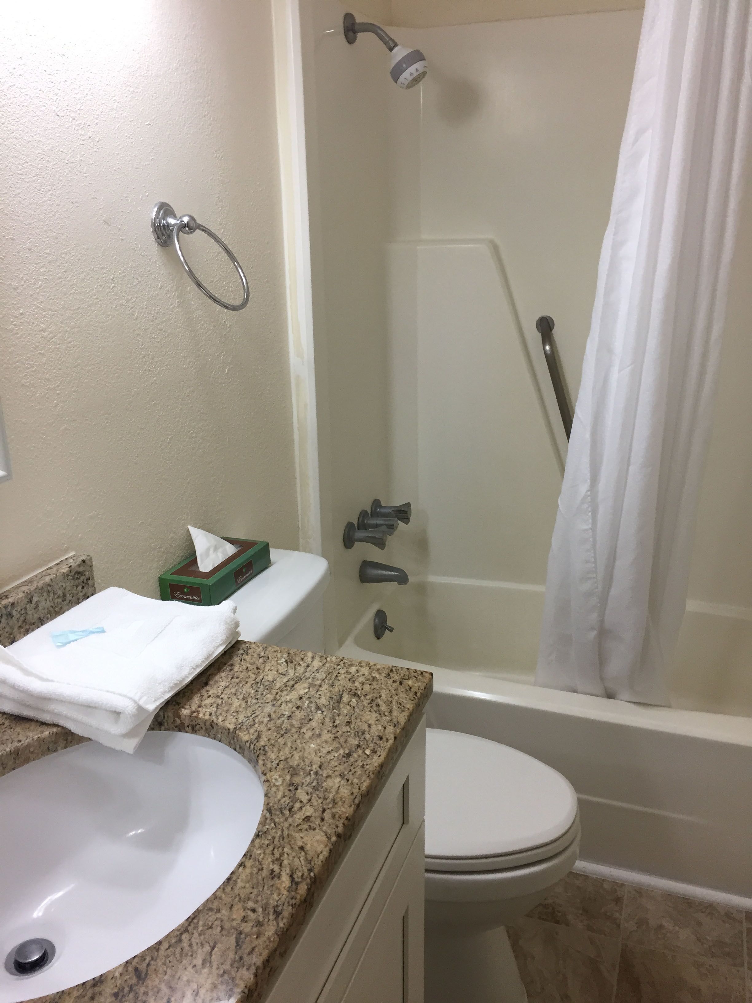 Une salle de bain avec un lavabo, des toilettes, une douche et une serviette posée sur le comptoir.