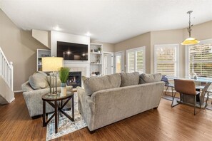 Un salon comprenant un canapé, une table basse, une cheminée et un coin repas avec une table et des chaises.