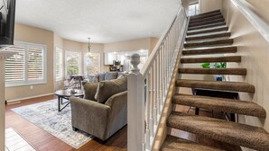 A spacious living room with a grey sofa, a coffee table, and a staircase with a unique carpeted design.