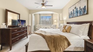 Une chambre d’hôtel avec un grand lit, une commode, un téléviseur et un tableau représentant un paysage urbain.