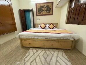 A bedroom with a wooden bed, a patterned rug, and a wall-mounted elephant artwork.