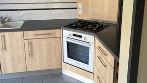 A kitchen with a built-in oven, a microwave, and a gas stove. - Chambre Chez Lhabitant (Cholet)