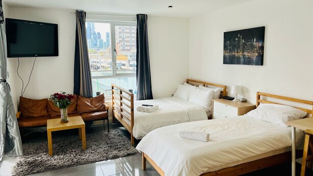 A hotel room with two beds, a sofa, a TV, and a city view. - London Bridge: Private Rooftop Terrace 3BR-7Guests (London)