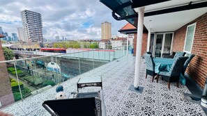Un balcon avec des carreaux de sol à motifs, une table avec des chaises et une vue sur un paysage urbain avec des bâtiments et un pont.