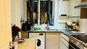 A compact kitchen with a built-in washing machine, a microwave, and a stove. - London Bridge: Private Rooftop Terrace 3BR-7Guests (London)
