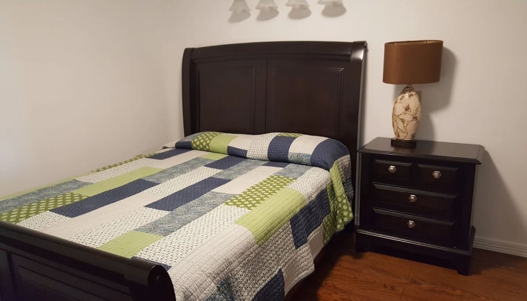 A bedroom with a bed, a nightstand, and a lamp.