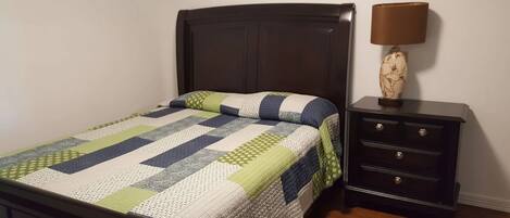 A bedroom with a bed, a nightstand, and a lamp.