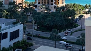 Un immeuble de grande hauteur doté de nombreux balcons, offrant une vue sur l’océan et bordé de palmiers.