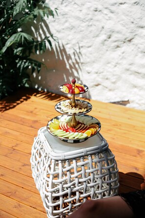 A tiered fruit and nut display on a wicker table outdoors. - DBD Hotel Çeşme (Cesme)