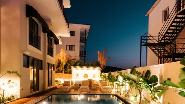 A modern pool area with a clear view of the pool, surrounding plants, and a building with a staircase. - DBD Hotel Çeşme (Cesme)