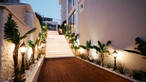 A wooden pathway leading to a building with white walls and a staircase. - DBD Hotel Çeşme (Cesme)