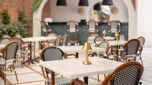 A restaurant with brick walls, white marble tables, and wicker chairs. - DBD Hotel Çeşme (Cesme)
