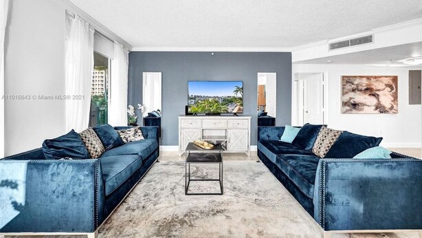 A modern living room with two blue sofas, a white entertainment unit, and a large TV. - LUXURY KINGDAVID*3/2H*KINGBEDROOM*BEST LOCATION (Sunny Isles Beach)
