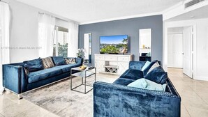 A modern living room with two blue sofas, a coffee table, and a flat-screen TV on a white cabinet. - LUXURY KINGDAVID*3/2H*KINGBEDROOM*BEST LOCATION (Sunny Isles Beach)
