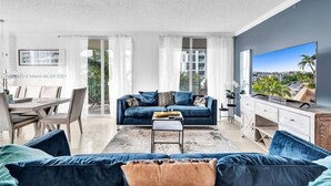 A modern living room with a blue sofa, a coffee table, and a TV on a wooden cabinet. - LUXURY KINGDAVID*3/2H*KINGBEDROOM*BEST LOCATION (Sunny Isles Beach)