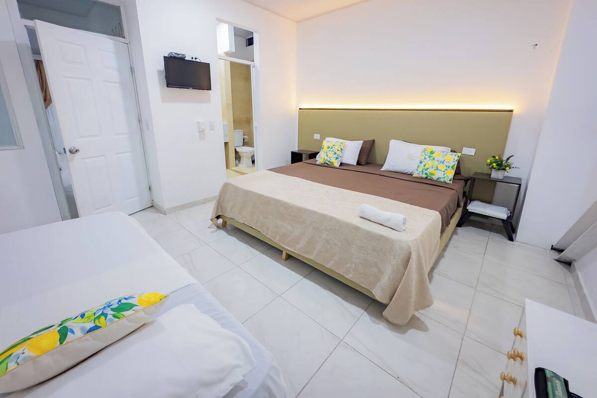 A hotel room with a bed, bedside tables, a mirror, and a television.