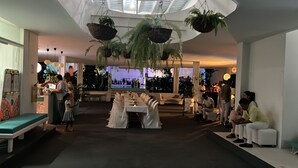A spacious indoor venue with a long dining table set for a formal event, surrounded by white chairs.