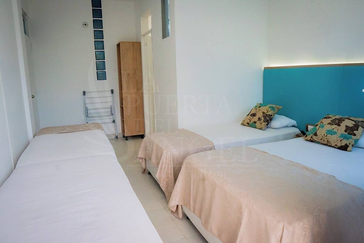 A hotel room with two single beds, a wooden wardrobe, a towel rack, and a view of the sea.