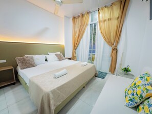 A hotel room with a bed, a nightstand, a window with curtains, and a small table with a plant. - La Puerta del Angel Isla  Club (Ricaurte)