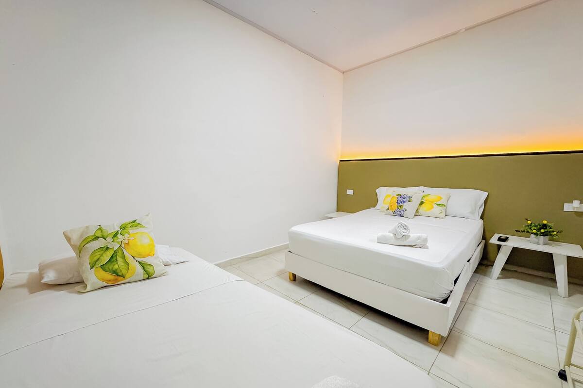 A modern hotel room with a neatly made bed, a bedside table with a lamp, and a small plant on the nightstand.