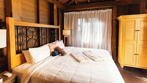 Ein schlichtes Schlafzimmer im Chalet-Stil mit Bett, Vorhängen und Kleiderschrank.