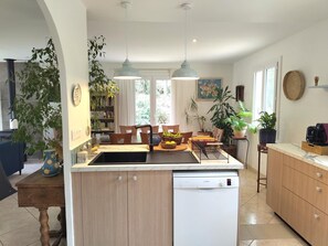 A modern kitchen with a dishwasher, a dining area with chairs, and a coffee machine.