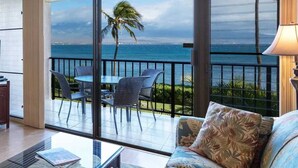 A balcony with a view of the ocean, a sofa, and a table with chairs. - Oceanfront, King Bed, Split AC, WiFi, Hot Tub Pool (Wailuku)