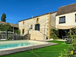 A stone building with a swimming pool, surrounded by a wooden fence and greenery. - Gite Moulin de Saint Sibournet Aux Portes du Périgord (Saint-Martin-de-Villeréal)