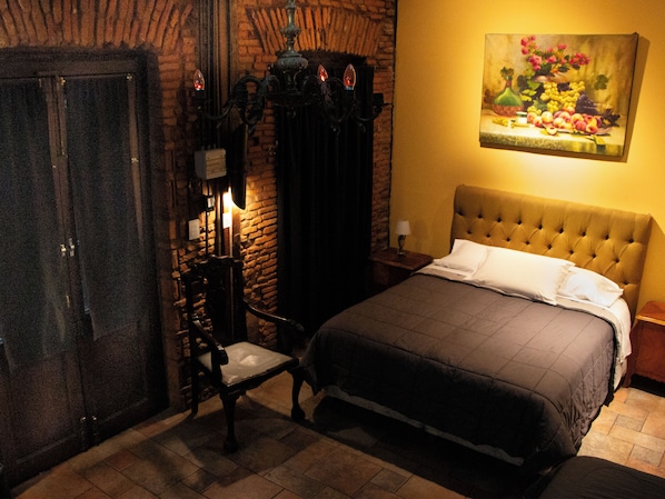 Una habitación con una cama, una silla, un cuadro y una puerta.