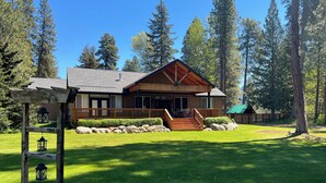 A lodge with a wooden exterior, a porch with chairs, and a stone pathway leading to the entrance.