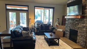 A living room with a fireplace, leather sofas, a coffee table, and large windows.