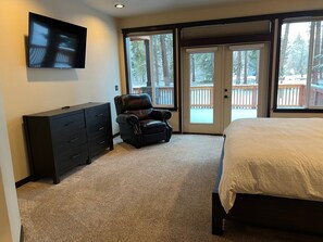 A bedroom with a bed, a dresser, a chair, and a TV mounted on the wall.