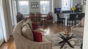 Ein geräumiges Wohnzimmer mit einem beige farbenen Sofa, einem Glastisch und einem gemusterten Teppich.