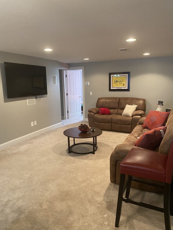 Ein Wohnzimmer mit einem braunen Ledersofa, einem Couchtisch und einem flachbildfernseher an der Wand.
