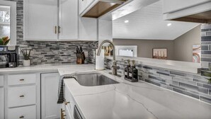 A modern kitchen with white cabinets, a granite countertop, and a tiled backsplash. - Pool - Hot Tub - Game Room - Sleeps 8 (Ashtabula)