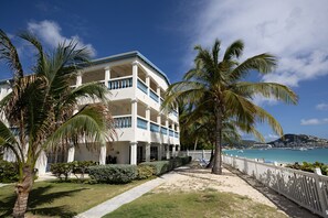 A beachfront hotel with a white facade, multiple balconies, and a sandy walkway leading to the beach. - 3 Bedrooms Duplex at Simpson Bay (Simpson Bay)