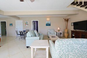 A living room with a sofa, armchair, dining table, and chairs. There is a television and a vase on a side table. - 3 Bedrooms Duplex at Simpson Bay (Simpson Bay)