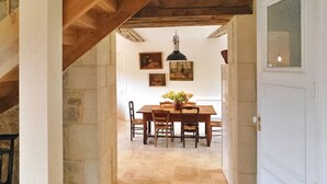 A dining area with a wooden table and chairs, a hanging pendant light, and framed artwork on the wall.