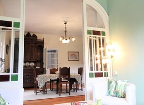 A dining area with a table, chairs, a chandelier, and a cabinet.