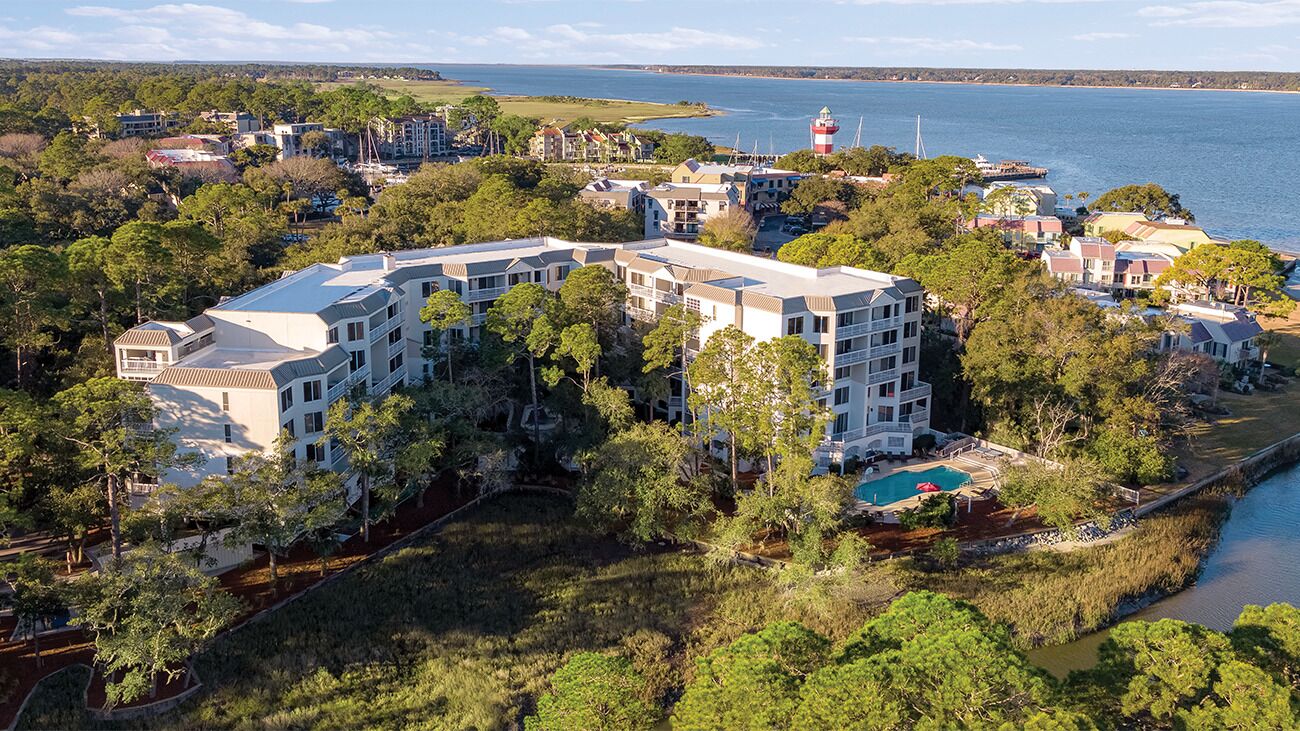 Een resort met een groot gebouw, omringd door bomen en water.