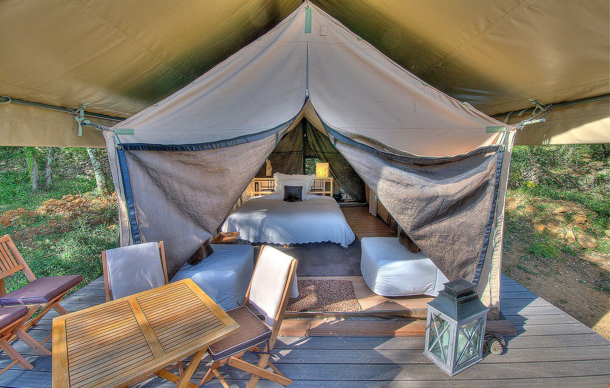 A tent with a bed, a table, and chairs.