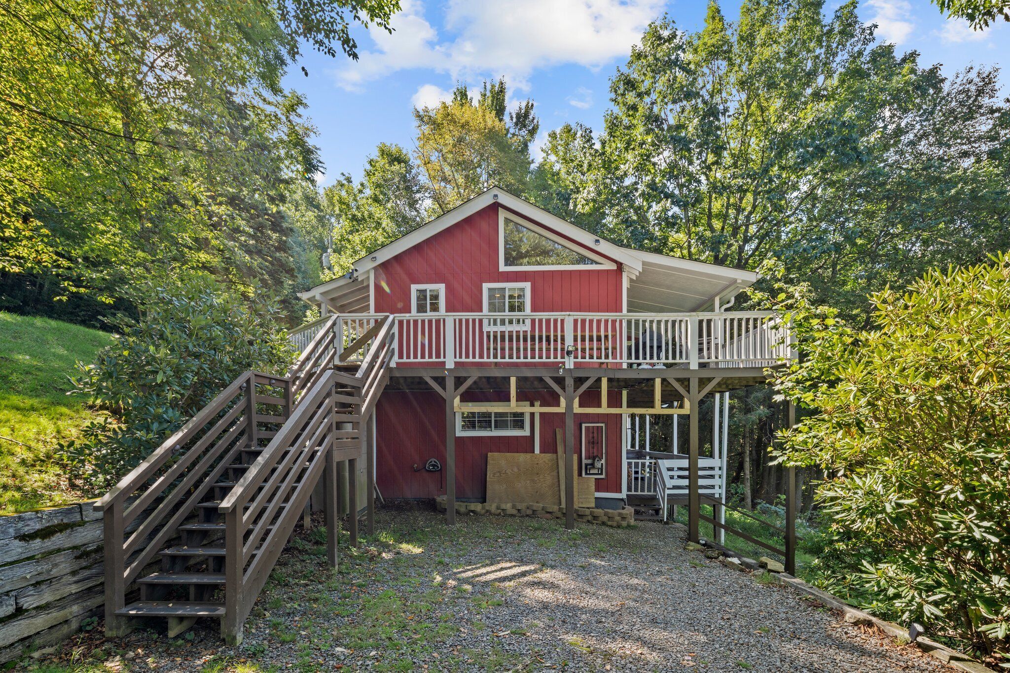 A red cabin with a wooden deck and a staircase leading to a balcony.